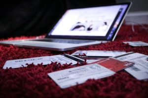 Laptop opened on bed with credit cards surrounding it