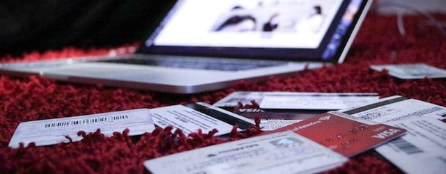 Laptop opened on bed with credit cards surrounding it