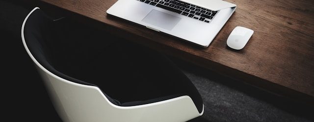 Empty desk chair in front of a laptop indicating someone being out of office